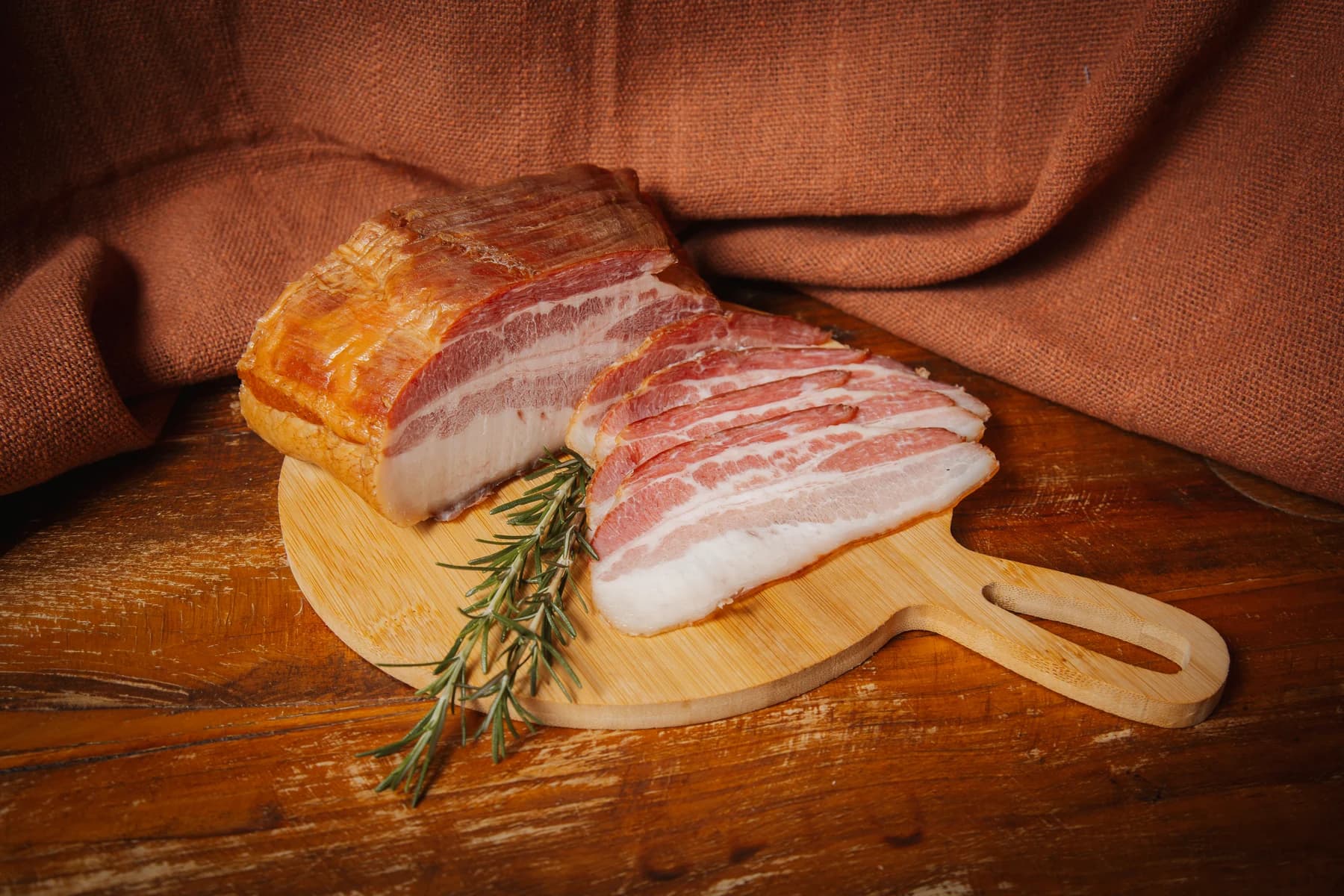 Bacon da Brutona em peça e fatias sobre uma tábua